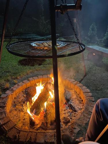 a fire pit with a table and a grill at Mazury Dom Oskar nad jeziorem Sasek Wielki z jakuzzi in Szczytno