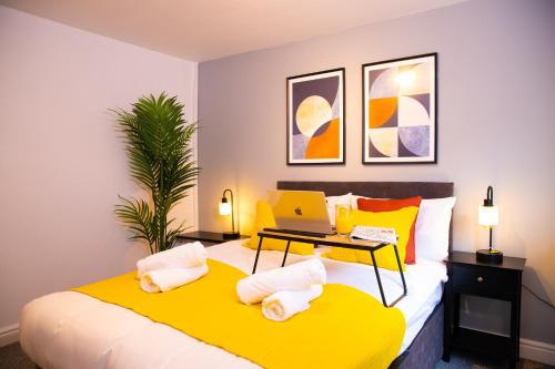 um quarto com uma cama amarela e um computador portátil. em Comfortable Stay for 6, Charming 3-Bedrooms near Gloucester Quays with Parking em Hempstead
