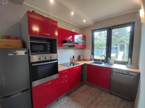 a kitchen with red cabinets and a stove top oven at Mazury Dom Oskar nad jeziorem Sasek Wielki in Szczytno