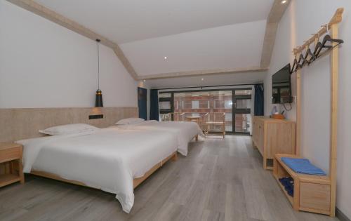 a bedroom with a large white bed and wooden floors at Cozy Boutique Hotel in Zhangjiajie