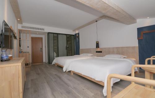 a large bedroom with two beds and a television at Cozy Boutique Hotel in Zhangjiajie