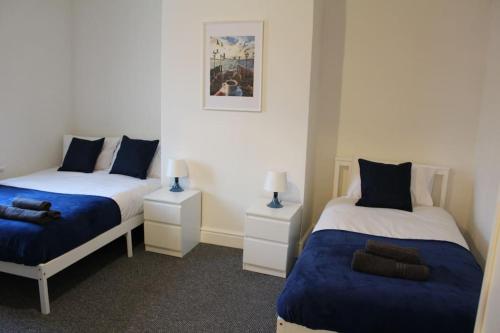 um quarto com 2 camas em azul e branco em Grove Bay Inn Home in Leeds - Harehills em Leeds