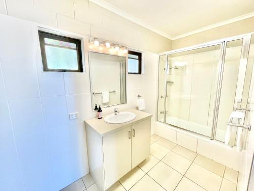 a white bathroom with a sink and a shower at Yongala Lodge by The Strand in Townsville