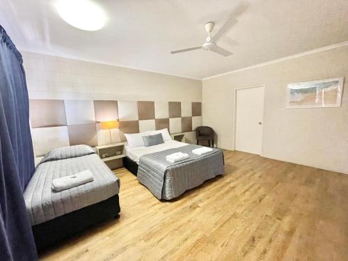 a bedroom with two beds and a ceiling fan at Yongala Lodge by The Strand in Townsville