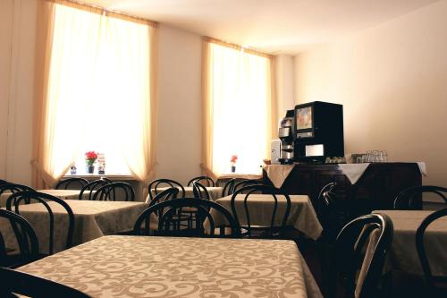 an empty room with tables and chairs and windows at Hotel Esperanza in Florence