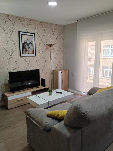 uma sala de estar com um sofá e uma televisão de ecrã plano em Urbanlux Recinto Ferial em Albacete