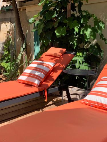 a bed with red and white pillows sitting next to a table at La villa des Amandiers in Hyères