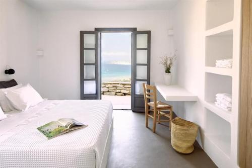 a bedroom with a bed and a table and a chair at Platinum Paros Villa - Villa Azure - 5 Bedrooms - Sea Views & Private Pool - Naoussa in Kolympithres