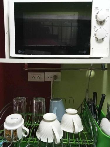 a kitchen counter with three cups and a microwave at City Capsule Hostel in Chiang Mai