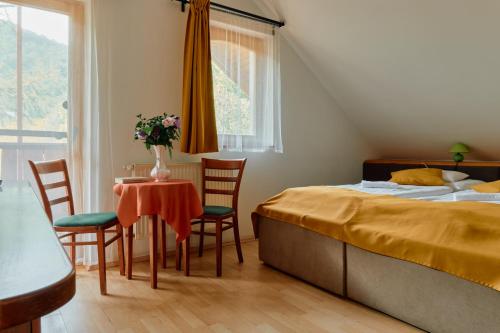 1 dormitorio con 1 cama, mesa y sillas en Öko-Park Panzió, Kemping és Rendezvényközpont, en Szarvaskő