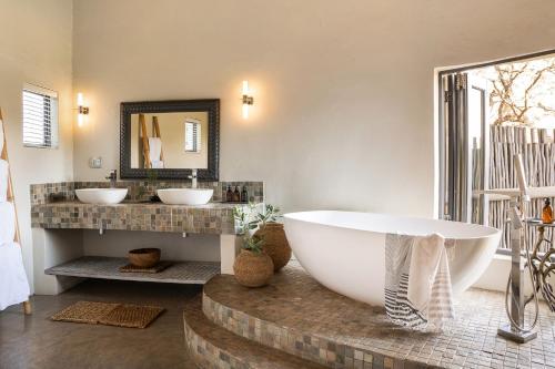 un bagno con una grande vasca e due lavandini di Simbavati River Lodge a Timbavati Game Reserve