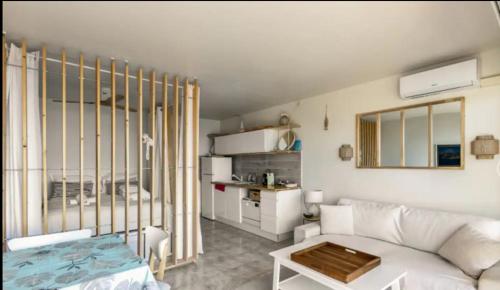 Petit Paradis sur la Mer في سانت رافائيل: غرفة معيشة مع أريكة بيضاء ومطبخ