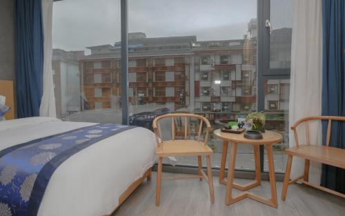 a bedroom with a bed and two chairs and a window at Cozy Boutique Hotel in Zhangjiajie