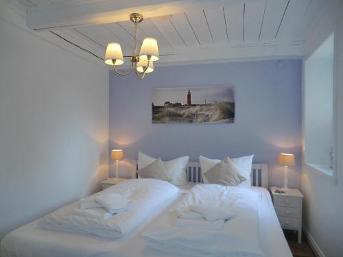 Schlafzimmer mit einem Bett mit weißer Bettwäsche und Kissen in der Unterkunft Seemöwe 5 Herrenhof in Wrixum
