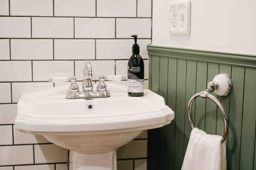 THE BEDFORD LODGE في إيزوميسانو: حمام مع حوض أبيض وزجاجة من النبيذ