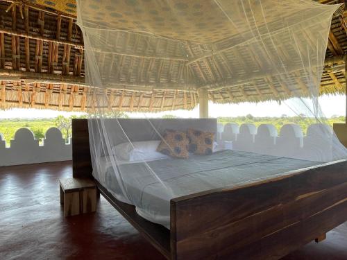 Pangani Cliffs Lodge في Pangani: غرفة نوم بسرير تحت سقف من القش