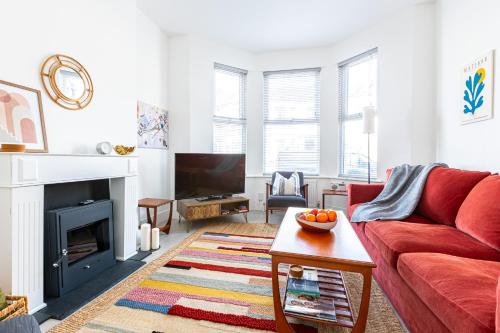 uma sala de estar com um sofá vermelho e uma lareira em Spacious 3BR House, 8 min Kensal Green, NW London em Londres