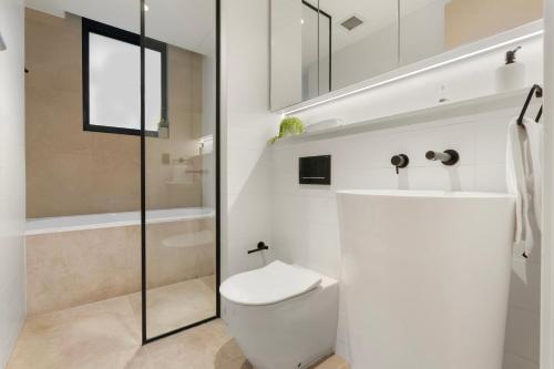 a white bathroom with a toilet and a shower at THE SHORE: COOGEE BEACH in Sydney