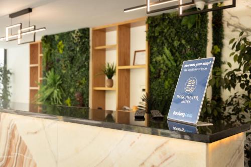 a sign on a counter in a lobby with plants at Dorchester Hotel in Sarandë