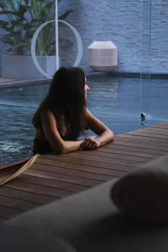 a woman sitting on a dock next to the water at Posia Retreat & Spa UNA Esperienze in San Foca