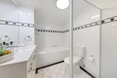 a white bathroom with a toilet and a sink at Modern and Cosy Sydney CBD Studio in Central in Sydney
