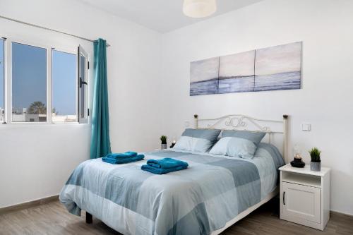a bedroom with a bed with blue sheets and a window at Viviendas El Pescador - Ancla in El Golfo