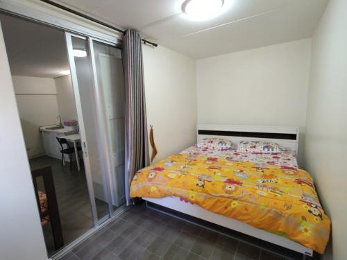 a bedroom with a bed with a yellow blanket at ป็อปปูล่าคอนโด เมืองทองธานี ใกล้ Impact 酒店 公寓 in Thung Si Kan