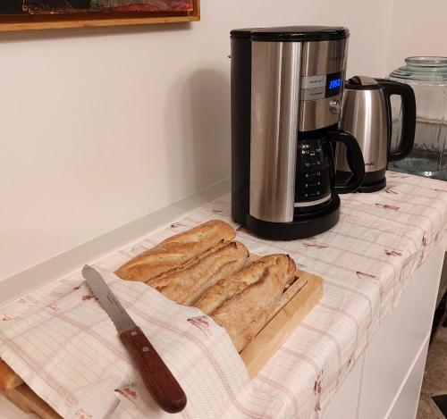 a pile of bread on a counter next to a coffee maker at LES JACQUEMARTS NORMANDS Maison d'hôtes - Guesthouse in Belmesnil