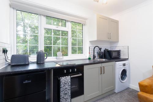 une cuisine avec des placards blancs et un comptoir noir dans l'établissement No4a, Cosy Studio Escape in Central Bedworth, à Bedworth