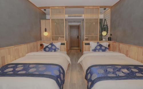 a room with two beds with blue and white sheets at Cozy Boutique Hotel in Zhangjiajie