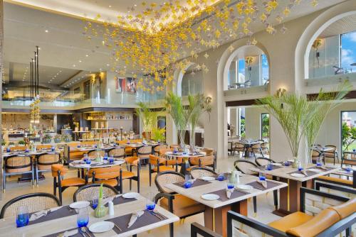 a restaurant with tables and chairs and a chandelier at Pramod Lands End Resort, a member of Radisson Individuals in Gopālpur