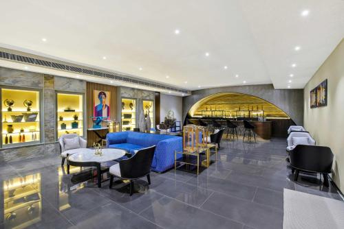 a restaurant with a blue couch and tables and chairs at Pramod Lands End Resort, a member of Radisson Individuals in Gopālpur