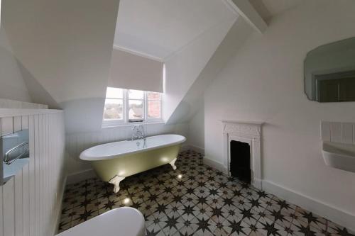 a white bathroom with a tub and a fireplace at Beautiful house, Cirencester centre, parking in Cirencester