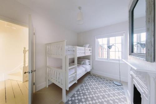 Habitación blanca con litera y ventana en Beautiful house, Cirencester centre, parking, en Cirencester