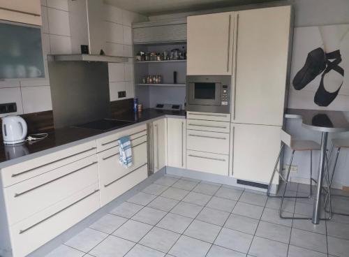 a kitchen with white cabinets and a white tile floor at Private Room in Esch-sur-Alzette in Esch-sur-Alzette