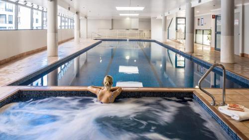 a woman is sitting in a swimming pool at Modern and Cosy Sydney CBD Studio in Central in Sydney