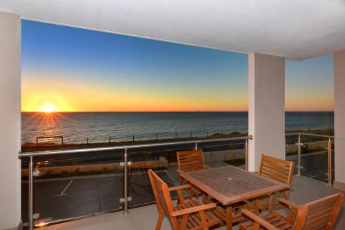a table and chairs on a balcony with a view of the ocean at Bunbury Seaview Apartments in Bunbury