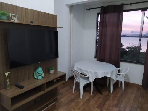 a living room with a table and a large television at Vista da Lagoa in Imbituba