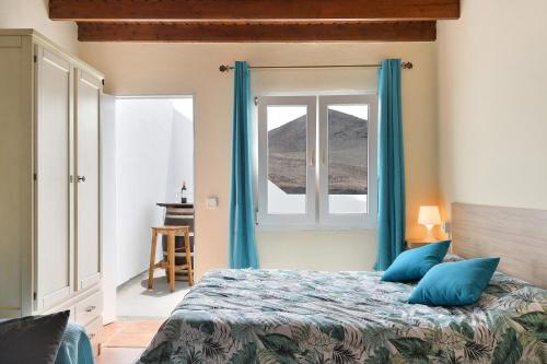 een slaapkamer met een bed met blauwe gordijnen en een raam bij Viviendas El Pescador - Timón in El Golfo