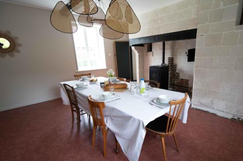 comedor con mesa con sillas y chimenea en Domaine des demoiselles - Chambres d'hôtes en Hauteville