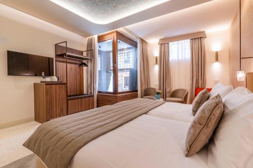a bedroom with a large white bed and a television at Palazzo Keller in Venice