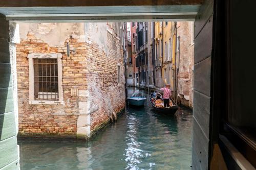 a man riding a gondola down a canal in a tunnel at Palazzo Keller in Venice