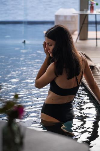 a woman in a bikini sitting in the water at Posia Retreat & Spa UNA Esperienze in San Foca
