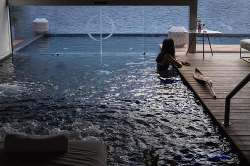 a woman sitting in the water in a swimming pool at Posia Retreat & Spa UNA Esperienze in San Foca