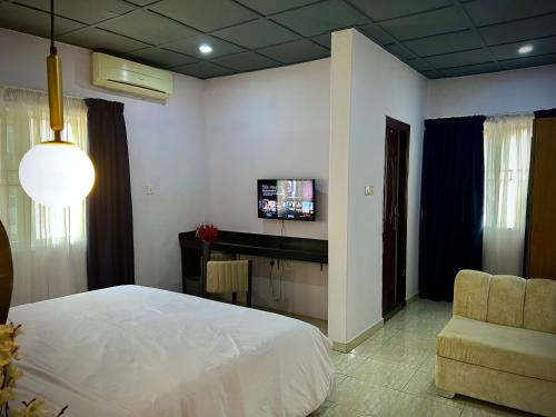 ein Schlafzimmer mit einem Bett und einem TV an der Wand in der Unterkunft The Orange Door Annex 2 in Lekki