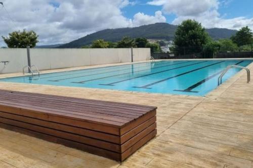a large swimming pool with a wooden bench around it at Apartamento Vila de Neda in Neda
