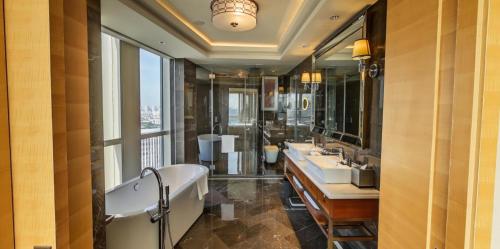 uma casa de banho com 3 lavatórios, uma banheira e uma grande janela. em Sheraton Petaling Jaya Hotel em Petaling Jaya