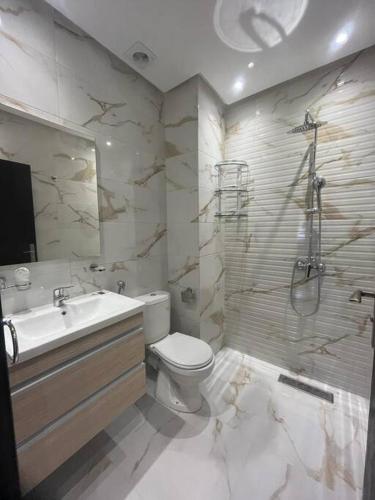 a bathroom with a toilet and a sink and a shower at bon vivant, calme, famille, équipé, clim, TV, parking, parc, agadir, 7 personnes, stylé, wifi portable in Agadir