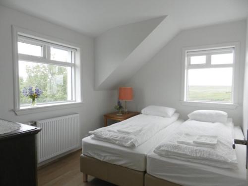 a white bedroom with two beds and two windows at Farmhouse Meiri-Tunga 1 in Hella