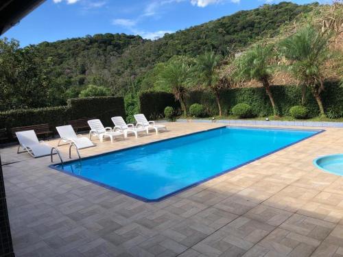 a swimming pool with lounge chairs next to a mountain at Chácara espaçosa e aconchegante em Juquitiba Sp in Juquitiba
